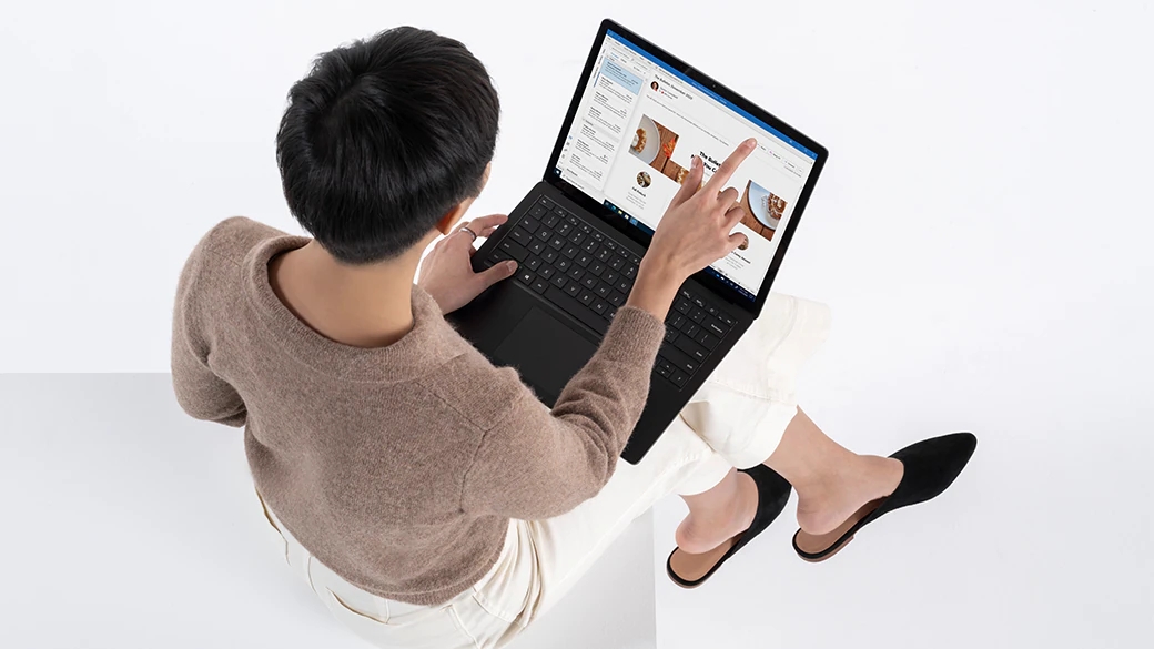 一个人坐着将 Surface Laptop 4 商用版放在腿上使用。
